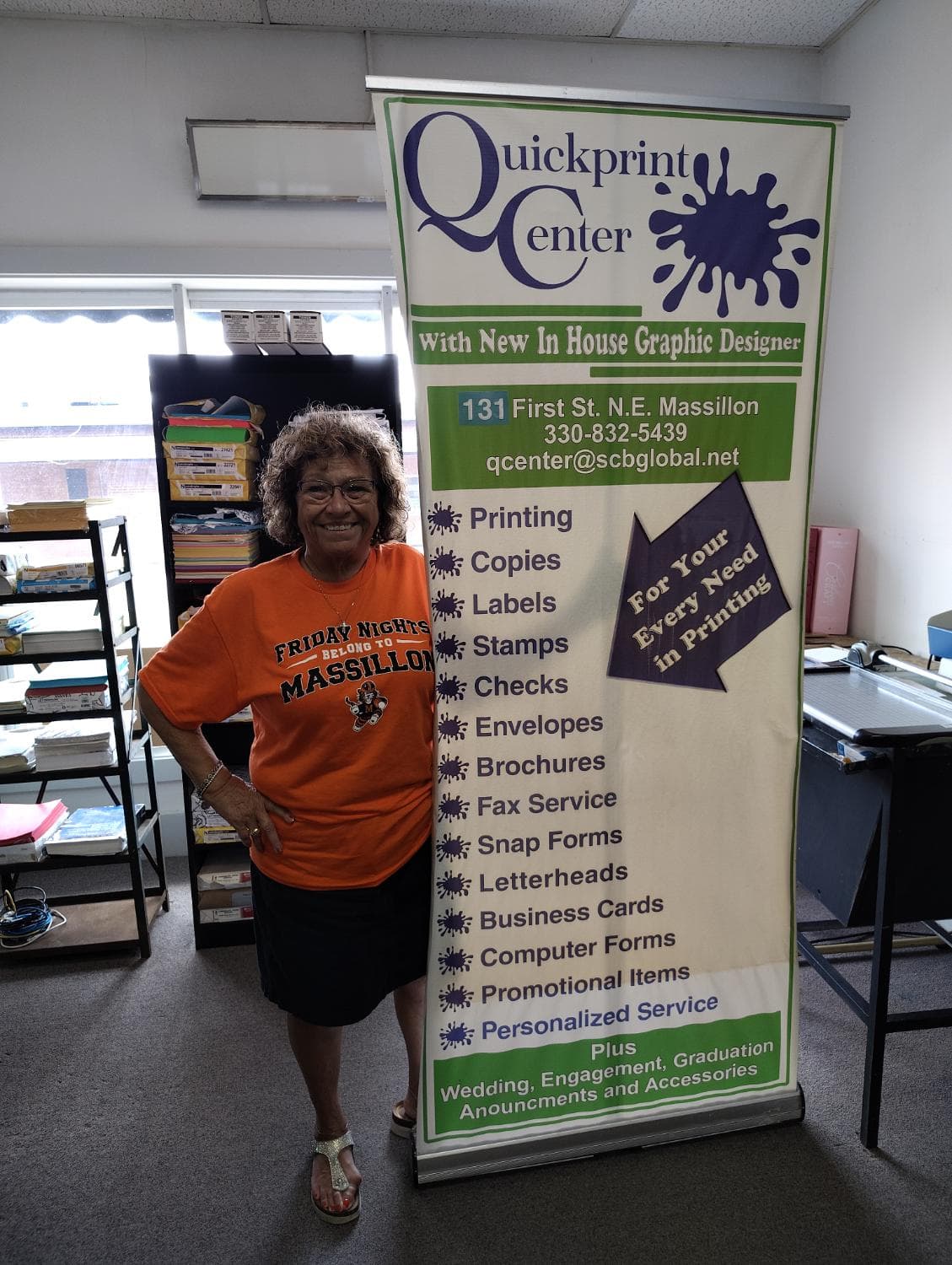 Sarita Cunningham standing beside the Quickprint Center shop banner