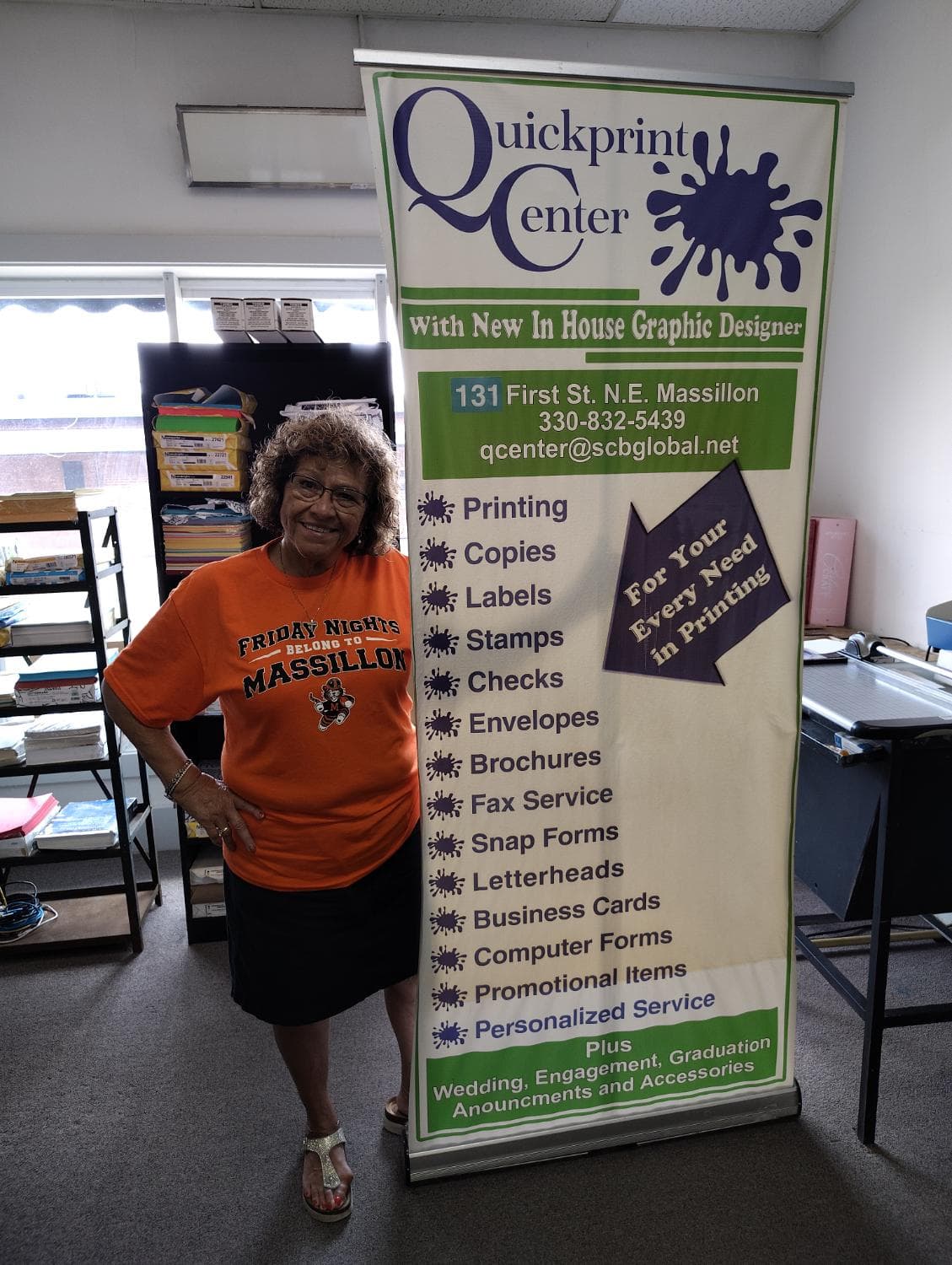 Sarita beside the Quickprint Center banner listing printing services